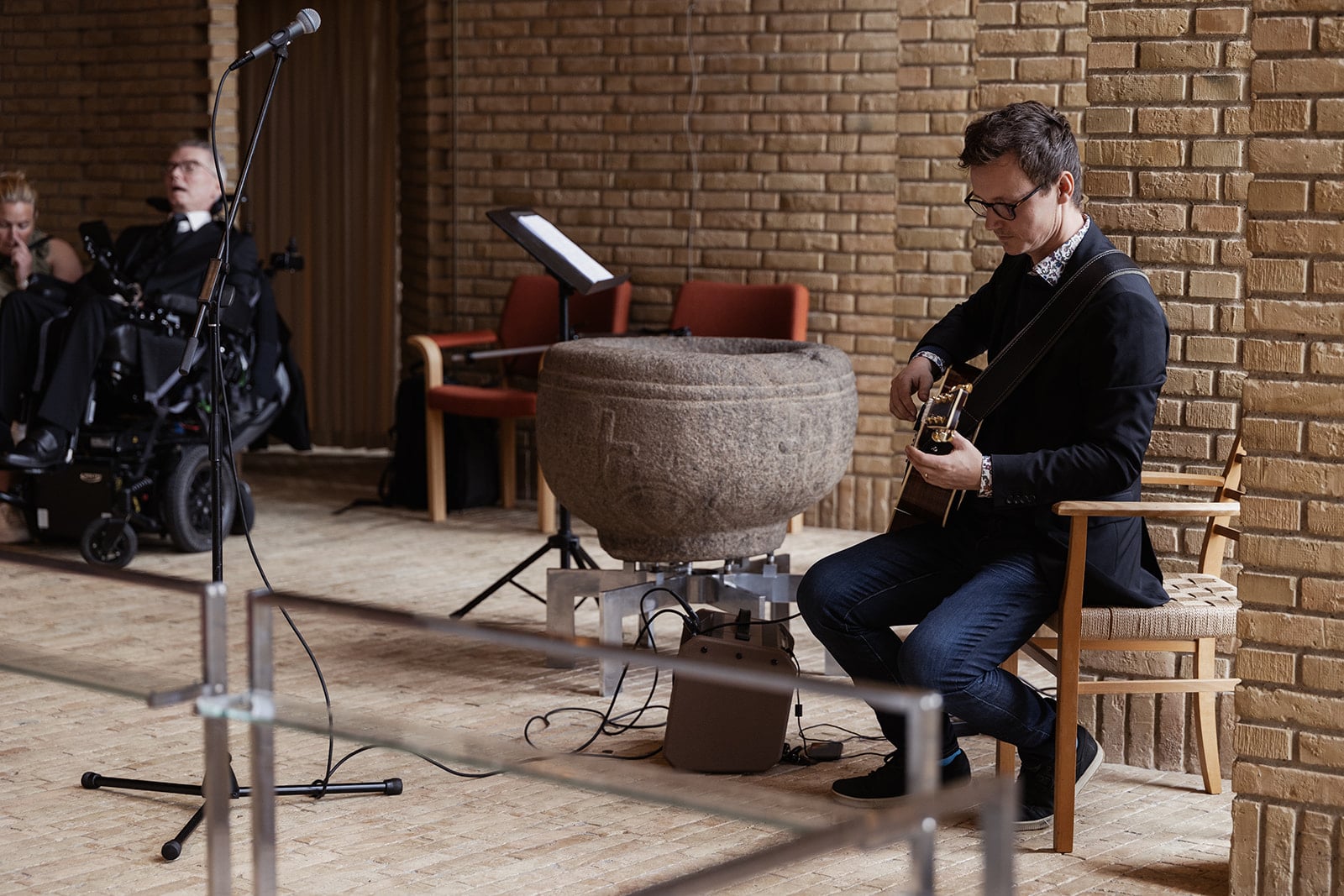 Mikkel Julius stemmer sin guitar i et kirkerum